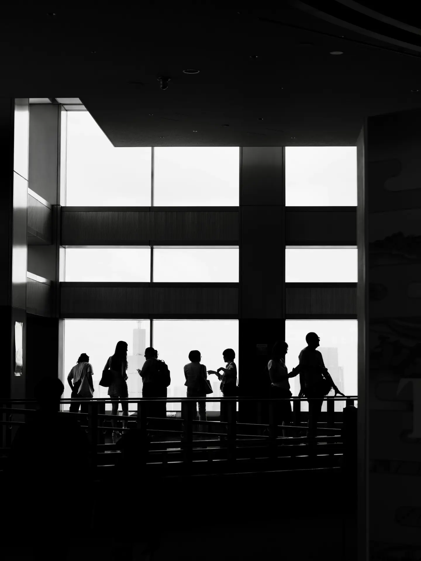 Observers silhouetted against a wall of windows overlooking a city skyline